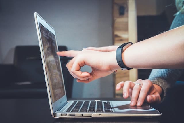 two people pointing at laptop screen inside Utah office