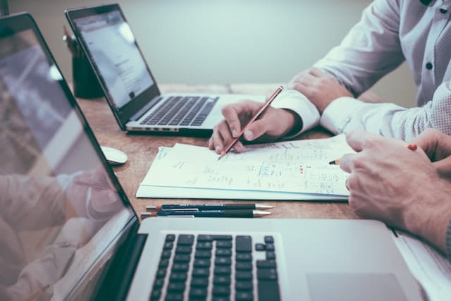 two IT professionals in Utah consulting with laptops and paper and pen