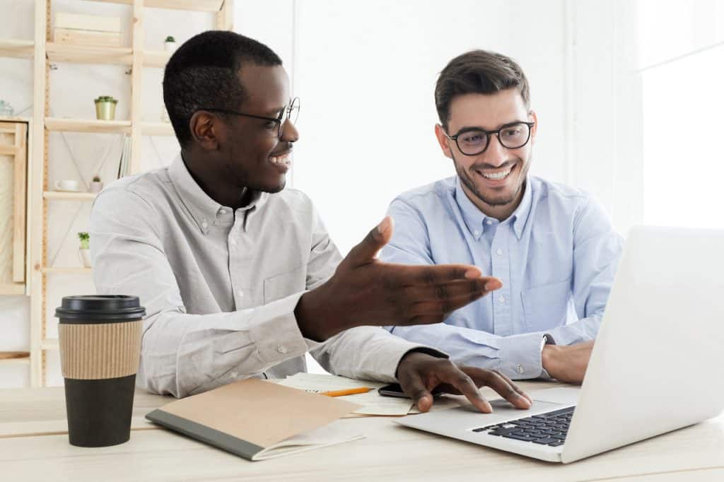 two male business colleagues at desk at work researching IT companies