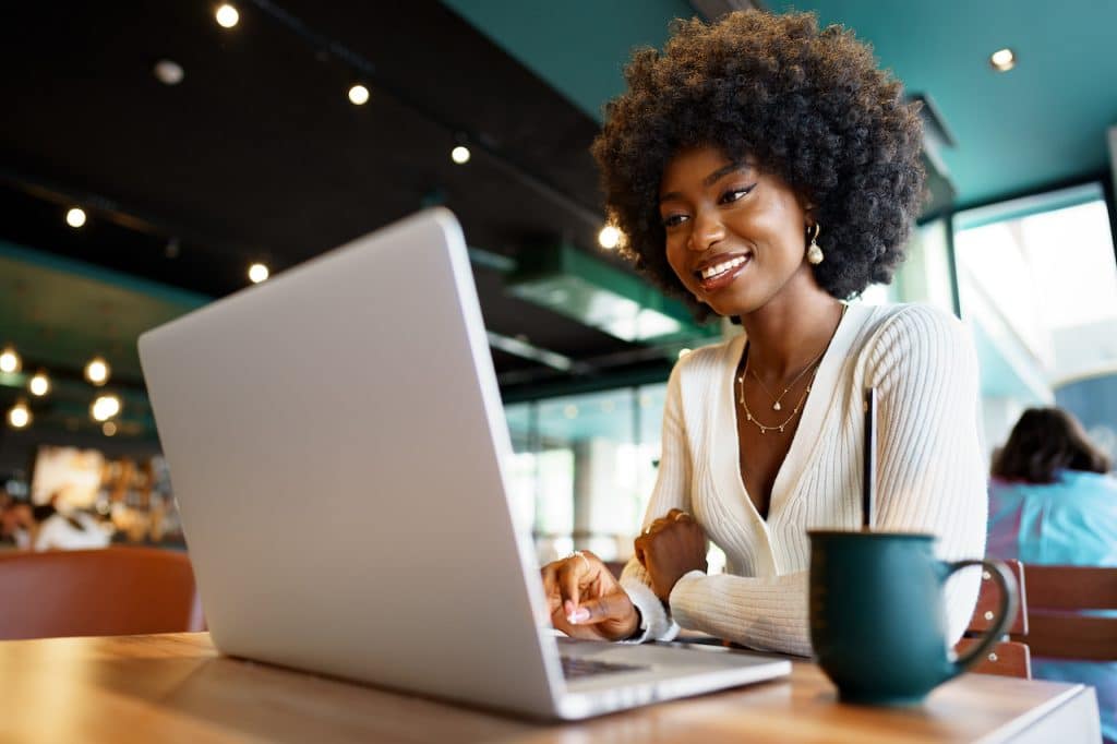 woman at cafe working on computer using outsourced IT support