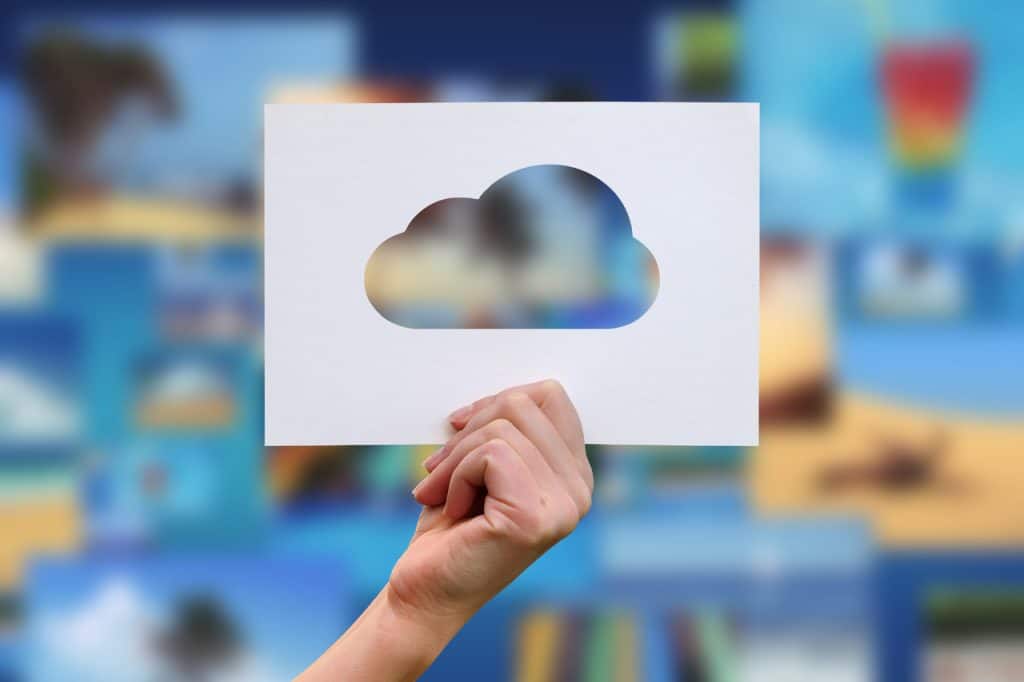 Female hand holding cloud perforated paper craft to represent the cloud vs local server