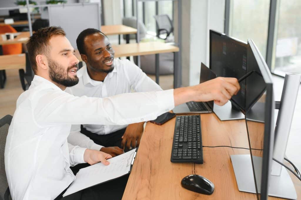 two coworkers in office at computer reviewing signs of a phishing email