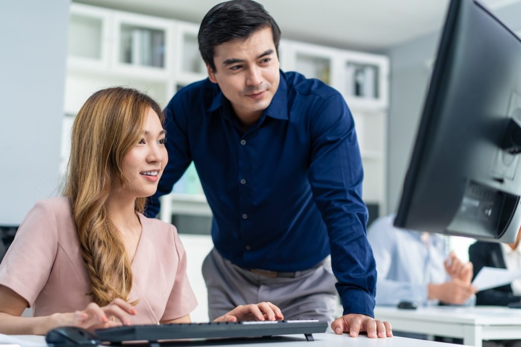 two coworkers working on computer having task discussion
